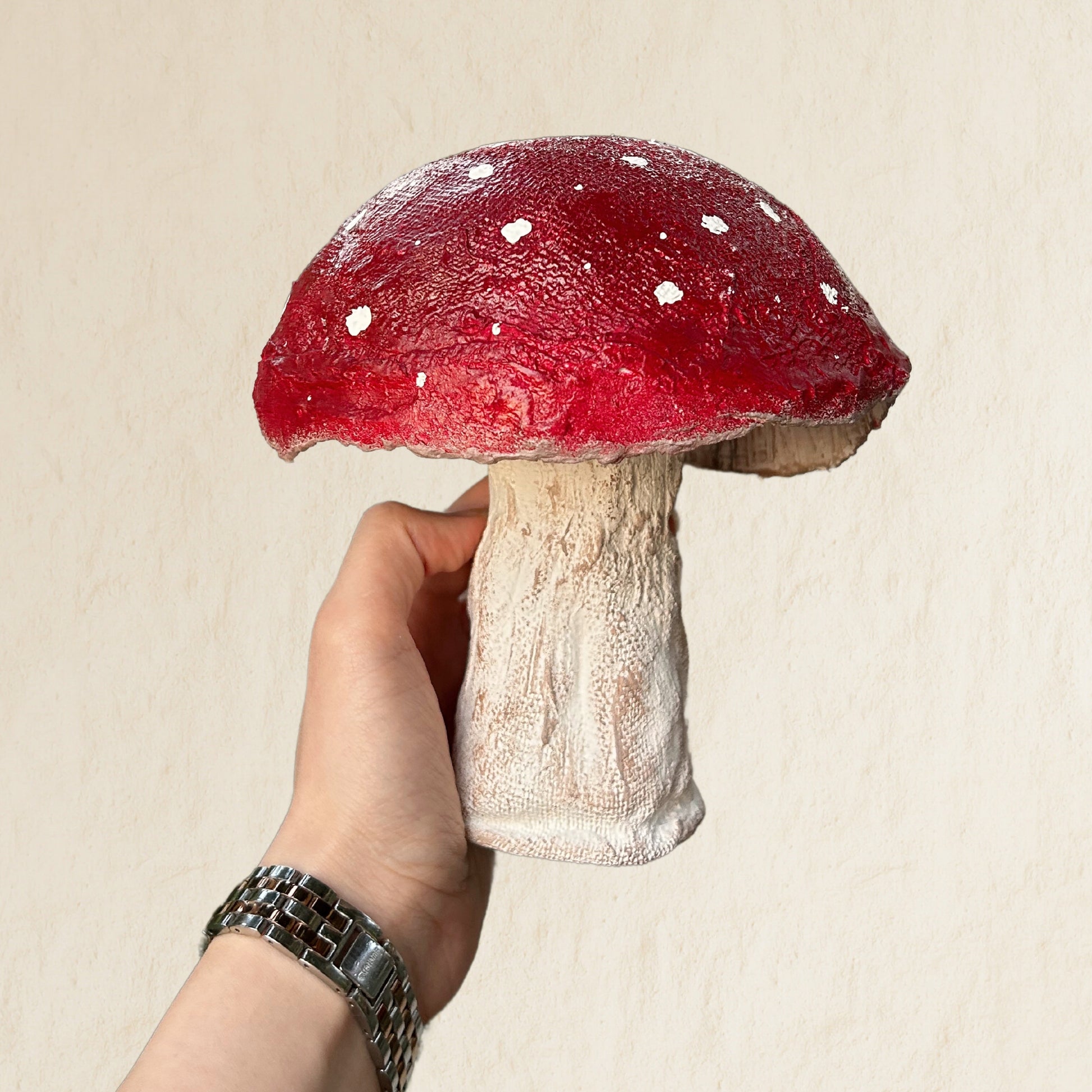  Studio-style view of handmade mushroom being held with white backdrop